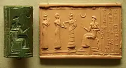 Sumerian cylinder seal and impression, dated c. 2100 BC, of Ḫašḫamer, ensi (governor) of Iškun-Sin c. 2100 BC. The seated figure is probably king Ur-Nammu, bestowing the governorship on Ḫašḫamer, who is led before him by Lamma (protective goddess).[351]
